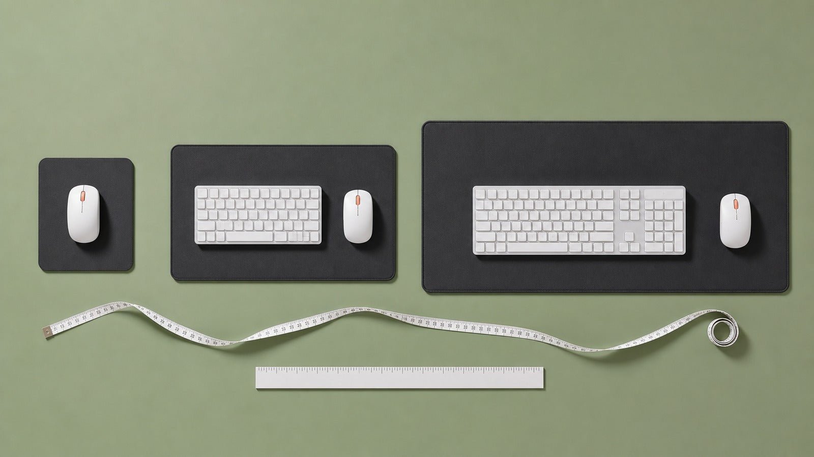 Three desk mat sizes compared from above with keyboards, mice, ruler, and measuring tape